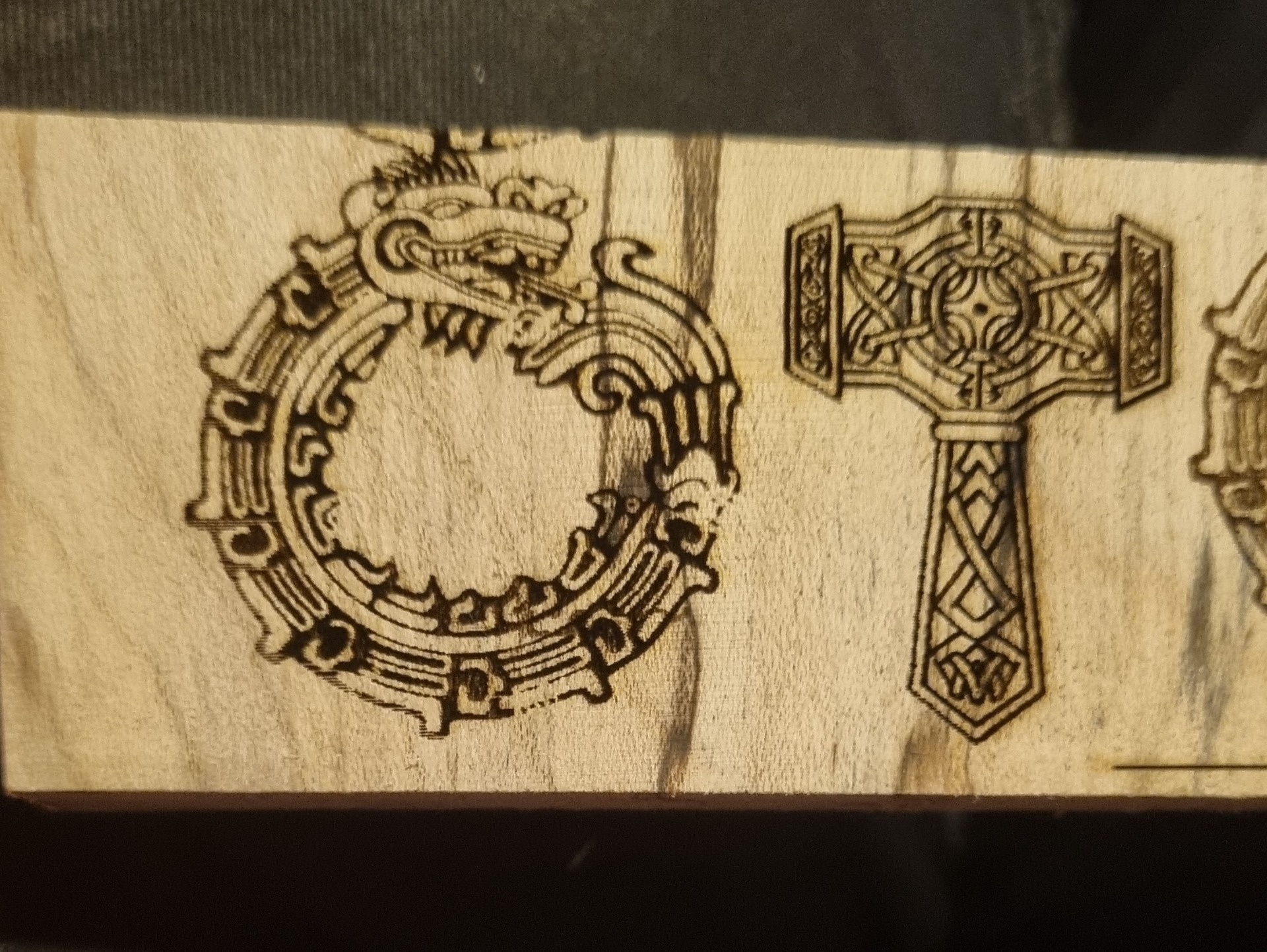 Laser engraved wooden pendants being carved to cut out and hang as pendants.